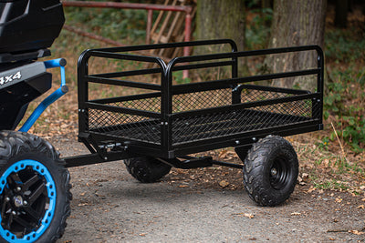 Black metal trailer attached to a four-wheeler in a forest 
