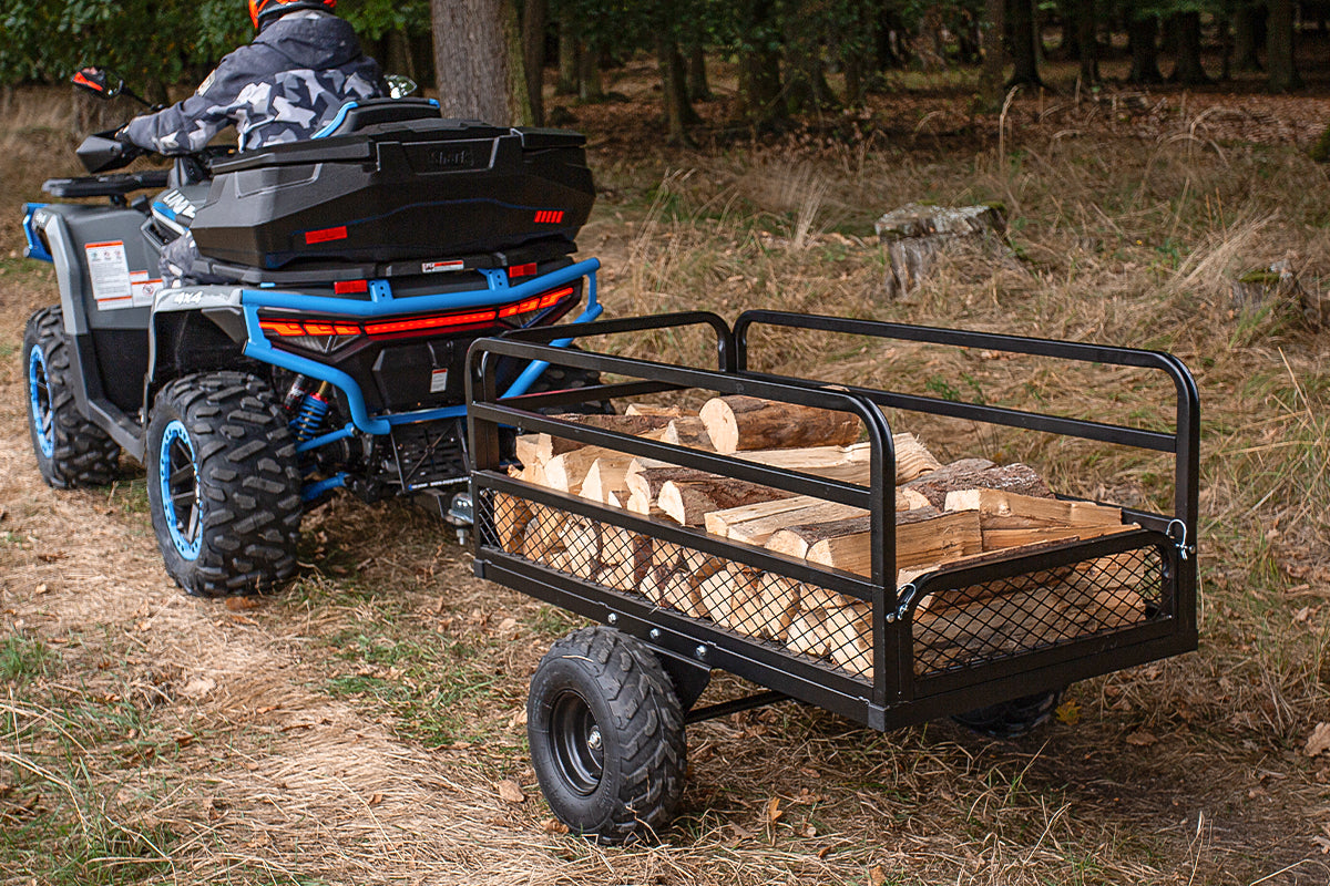 ATV with a trailer carrying wood in a forest setting