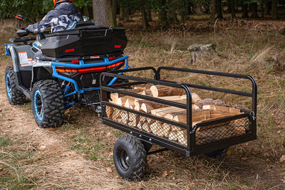 ATV with a trailer carrying wood in a forest setting